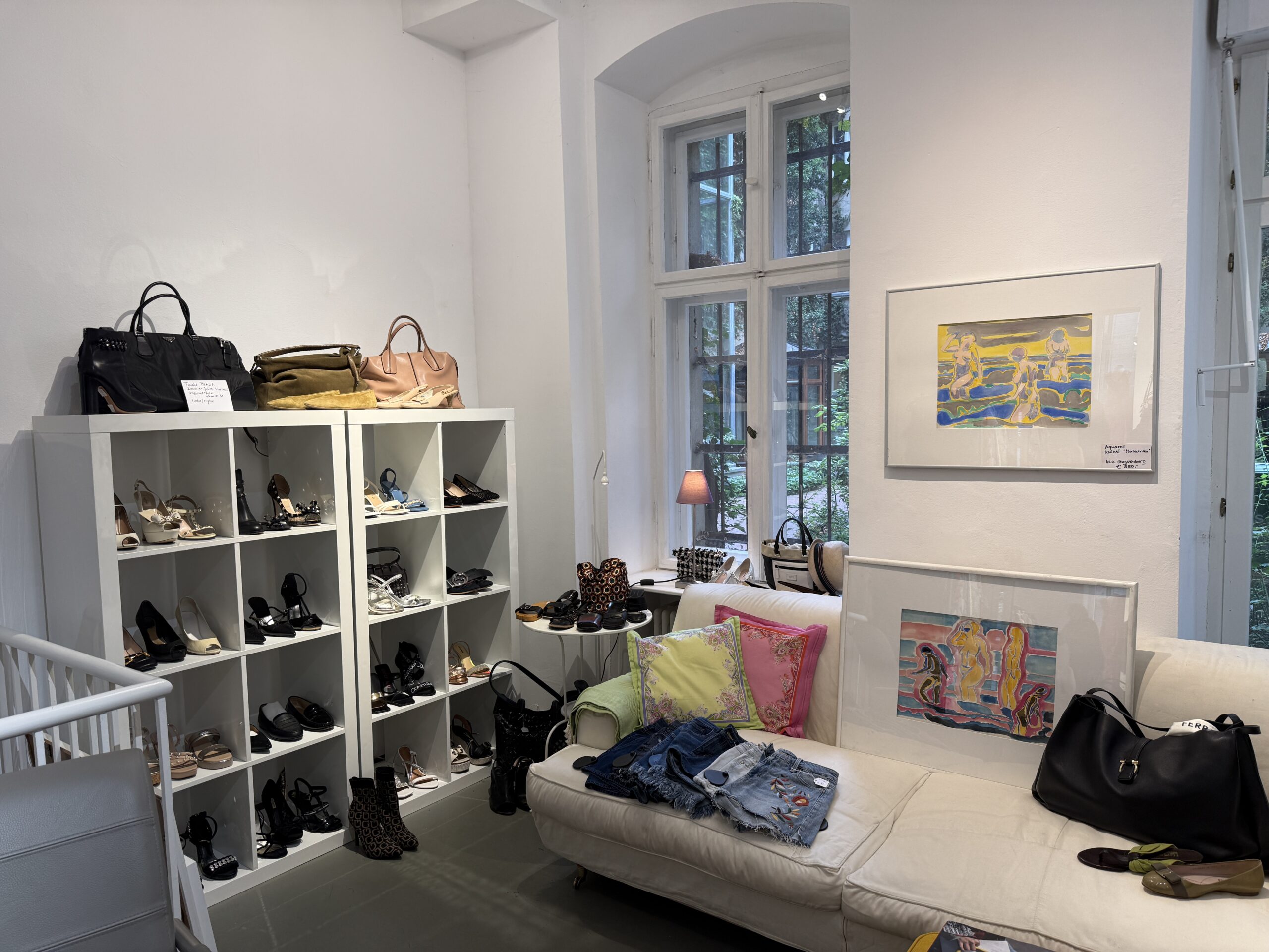 Sitzecke im Laden von ARTEMODA mit Originalgemälden, Schuhregal und Tageslicht